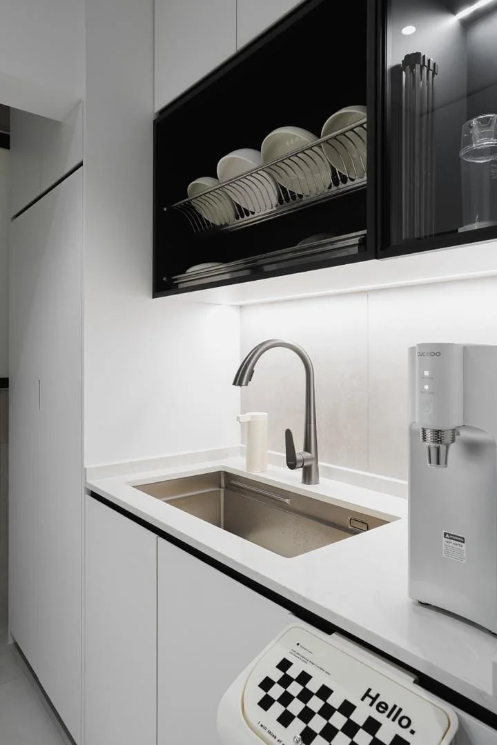 Kitchen features: single-bowl stainless-steel sink, chrome pull-down faucet, white cabinetry, black glass upper cabinets, white countertop, built-in water dispenser, dish rack above sink, LED under-cabinet lighting, grey wall tiles, ceramic tile flooring; style: modern.